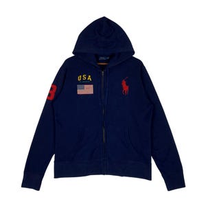 May include: A navy blue zip-up hoodie featuring a hood, long sleeves, and two front pockets. The chest displays the text USA in yellow, a small American flag patch, and a red embroidered polo player logo. A large red number 3 is on the sleeve.