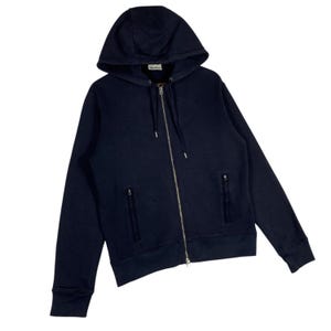 May include: Navy blue zip-up hoodie with a drawstring hood and two front pockets. The hoodie has a silver zipper and a small label near the hood. A casual outerwear garment.
