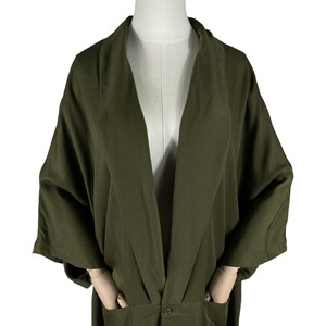 Puede incluir: Bata estilo kimono verde oliva con mangas anchas y corte holgado. La bata tiene dos bolsillos delanteros y un cierre de bot&oacute;n &uacute;nico en la cintura. La tela tiene un brillo sutil.