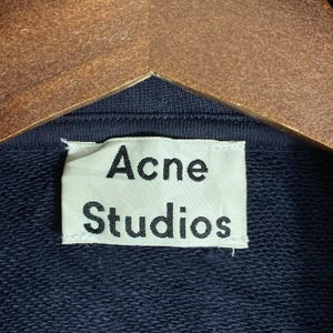 May include: A white ceramic mug with a black handle and the text "But First, Coffee" in a black, bold font. The mug is on a white surface.