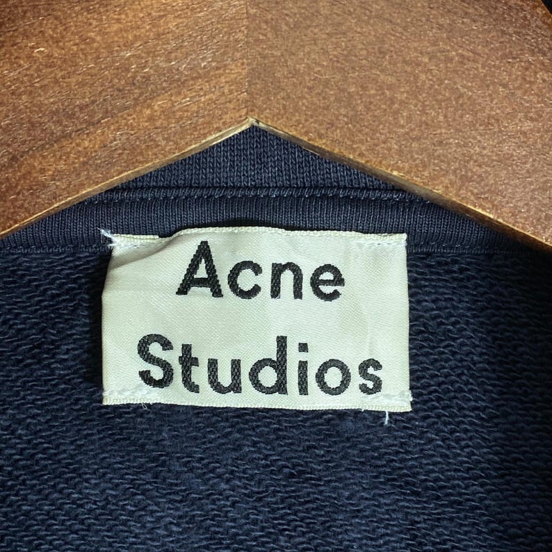 May include: A white ceramic mug with a black handle and the text "But First, Coffee" in a black, bold font. The mug is on a white surface.