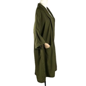 Puede incluir: Abrigo largo verde oliva con cuello chal y dos bolsillos delanteros. El abrigo tiene mangas tres cuartos y un corte holgado. La tela parece ser un material ligero, adecuado para superponer. El abrigo se exhibe en un maniqu&iacute;.