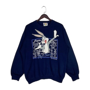 May include: A navy blue crewneck sweatshirt featuring a large graphic of Bugs Bunny in the center. The design includes multiple white line-art sketches of the character surrounding the main image, with the text Bugs Bunny printed below.