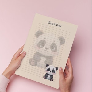 May include: A lined notebook with the text "Mary's Notes" at the top. The notebook features a large, cartoon panda illustration and a smaller panda illustration at the bottom. The background is a soft pink.