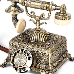 Könnte beinhalten: Ein antikes Drehscheibentelefon mit einem verzierten, geprägten Sockel aus bronzefarbenem Metall mit komplizierten Blumenmustern. Es umfasst einen passenden Hörer mit cremefarbenen Ohrstücken, eine schwarze Wählscheibe und ein braunes geflochtenes Kabel.