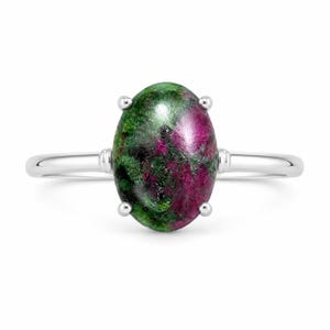 Pode incluir: Um anel de tom prateado com uma grande pedra preciosa em formato de cabochão oval, apresentando um padrão manchado de magenta profundo e verde floresta escuro. A pedra é fixada por um engaste de quatro garras numa banda de metal lisa e polida.