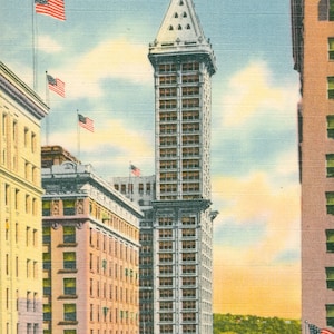 May include: Vintage postcard featuring the Smith Tower in Seattle, Washington. The tall, white building with a distinctive top is the focal point, surrounded by other buildings and American flags. The sky is a mix of blue and yellow.