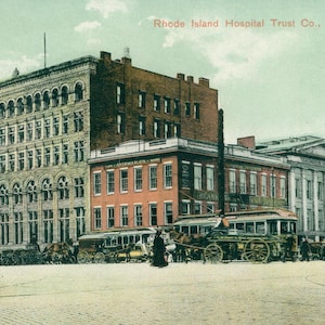 May include: A vintage postcard depicting a large brick building with the text "Rhode Island Hospital Trust Co., Providence, R.I."  The building has a large arched entrance and many windows. A vintage streetcar is parked in front of the building.