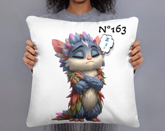 May include: White square pillow featuring a colorful cartoon creature with closed eyes and crossed arms. The creature has blue, pink, and green feathers and the text "N°163" is printed on the pillow.