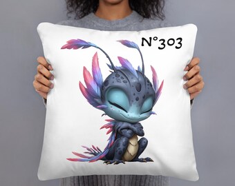 May include: White throw pillow featuring a cartoon creature with blue, purple, and pink accents. The creature has large eyes and is sitting with its arms crossed. The pillow has the number "N°303" printed in black.