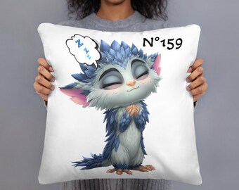 May include: White square pillow featuring a cartoon creature with blue and white fur, closed eyes, and a thought bubble with "zzz" above its head. The pillow has the number "159" printed in black.