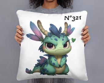 May include: White decorative pillow featuring a cartoon dragon with teal and green scales, blue and pink feathered accents, and large purple eyes. The pillow has the text "N°321" and a green heart.
