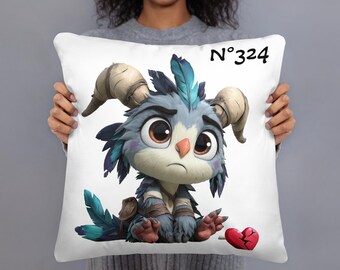 May include: White square pillow featuring a cartoon creature with blue and gray fur, large brown eyes, and curved horns. The creature sits beside a broken red heart. The text "N°324" is printed in black.