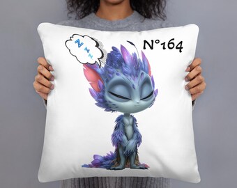 May include: White pillow featuring a cartoon creature with blue and purple fur, closed eyes, and a speech bubble with "Z"s. The pillow has the number "164" in black. The creature is in a sleeping pose.