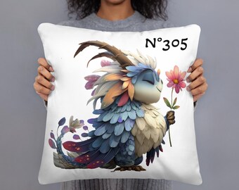 May include: White decorative pillow featuring a whimsical cartoon creature with blue, orange, and white feathers, holding a pink flower. The pillow has the number "N°305" printed in black.