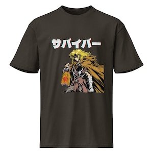 Puede incluir: Camiseta marrón oscuro con una ilustración de estilo manga de un personaje con cabello rubio, una capa marrón y una linterna. La palabra japonesa "サバイバー" (Survivor) está impresa en blanco con efecto 3D sobre el personaje.