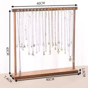 Op de afbeelding: Houten kettingstandaard, 40 cm breed en 40 cm hoog, met een basis van 7,4 cm. De standaard heeft haken om kettingen op te hangen. De bruine houten standaard bevat veel zilveren kettingen.