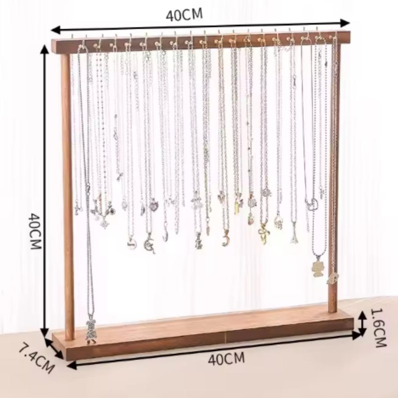Op de afbeelding: Houten kettingstandaard, 40 cm breed en 40 cm hoog, met een basis van 7,4 cm. De standaard heeft haken om kettingen op te hangen. De bruine houten standaard bevat veel zilveren kettingen.
