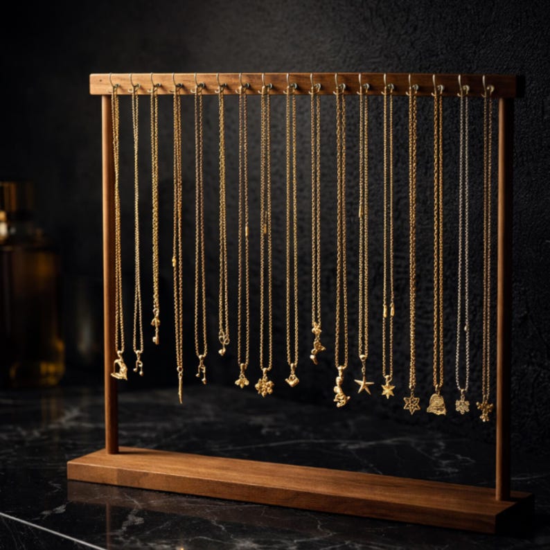 Op de afbeelding: Een houten sieradenstandaard met talrijke gouden kettingen met diverse hangerontwerpen. De kettingen hangen aan een horizontale balk en tonen een verscheidenheid aan bedels, waaronder sterren en bellen. De standaard is gemaakt van donker hout.