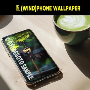 May include: A smartphone with a clear case displays a nature-themed wallpaper with a Japanese aesthetic. The phone is next to a green ceramic mug filled with matcha latte. The image includes the text "(WIND)PHONE WALLPAPER" and "@OFDEGOTO SAMPLE".