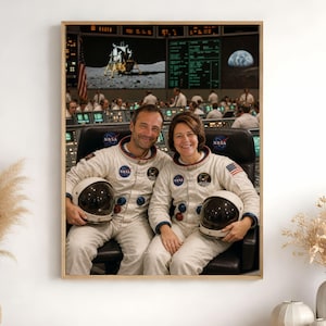 Peut inclure: Une impression d'art mural encadrée montrant deux personnes en combinaisons de vol spatial blanches de la NASA assises dans des sièges de contrôle de mission. Elles tiennent des casques blancs. L'arrière-plan affiche un module lunaire.