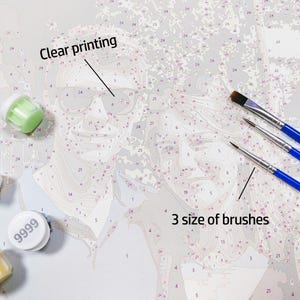 May include: A paint-by-numbers canvas featuring a line drawing of two faces with numbered sections, labeled with the text Clear printing. Included are three paint brushes with blue handles and several small round paint pots with white lids.