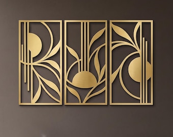 May include: A set of three rectangular gold-coloured metal wall panels featuring a cut-out design of stylised leaves, vertical lines, and semi-circular shapes. The panels are arranged side-by-side, creating a cohesive geometric pattern on the wall.