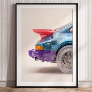 以下が含まれることがあります： 半透明のスポーツカーの後部を描いた額装アートプリント。車体はクリアブルーで、鮮やかな赤のリアスポイラー、紫のバンパー、内部の機械的なディテールが見える透明なホイールが特徴です。