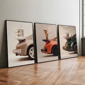 May include: Three framed art prints featuring the rear sections of sports cars. The first shows a beige car with an espresso machine on the spoiler, the second an orange car with a gold trophy, and the third a green car with a golf ball basket.