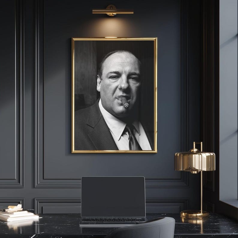 May include: A black and white portrait photograph of a man in a suit and tie with a cigar in his mouth, displayed in a thin gold frame. The subject has a serious expression, looking directly forward, captured in a high-contrast monochromatic style.