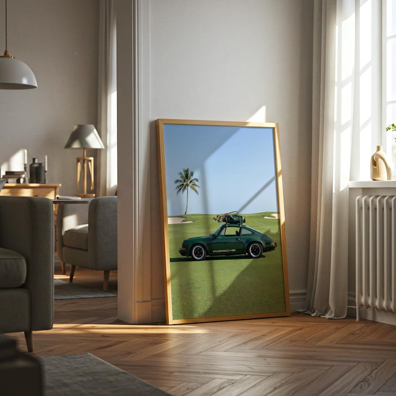 Puede incluir: Impresi&oacute;n enmarcada de un coche deportivo Porsche verde oscuro con equipaje en el techo, estacionado en un campo de golf verde bajo un cielo azul. Una palmera est&aacute; en el fondo. El marco es de madera clara.
