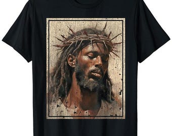 May include: Black t-shirt featuring a portrait of a person with long dreadlocks wearing a crown of thorns. The portrait is framed in a rectangular border with a distressed, vintage aesthetic. The person's eyes are closed, and they have a beard.