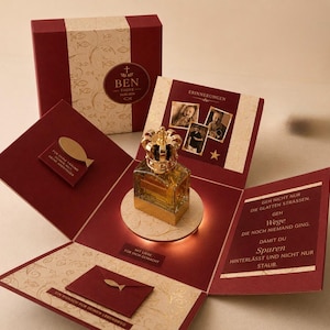 May include: A burgundy gift box with a gold crown-topped perfume bottle inside. The box features photos, the text BEN TAUFE 30.05.2024, and German inscriptions including ERINNERUNGEN and a quote about paths, along with gold fish icons and decorative patterns.