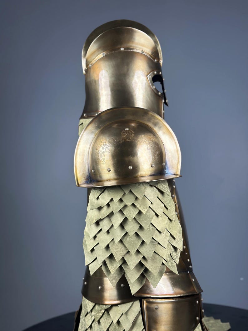 May include: A bronze-colored suit of armor, featuring a helmet, shoulder guards, and a scale-like skirt. The armor has a polished finish and is designed with intricate details, suggesting a historical or fantasy theme.
