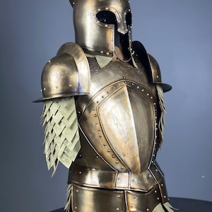 May include: A detailed bronze-colored suit of armor, featuring a helmet with eye openings and a decorative crest. The armor includes shoulder guards, a chest plate with embossed designs, and layered skirt-like elements. The overall design suggests a medieval or fantasy theme.