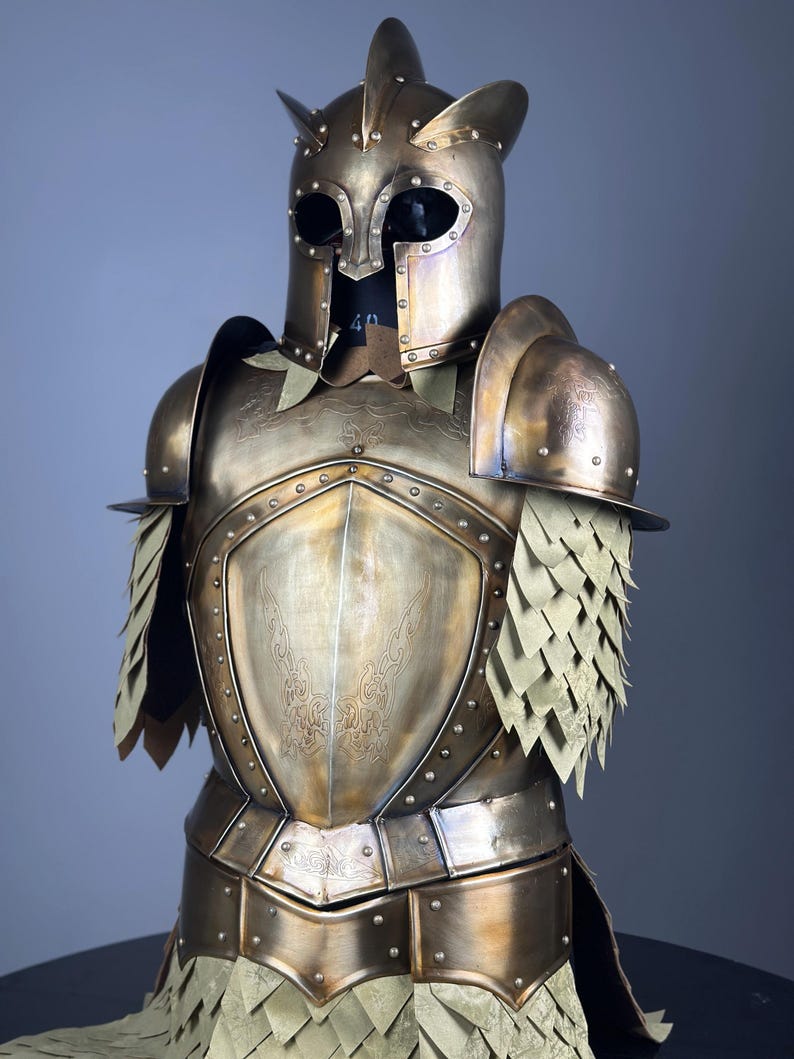 May include: A bronze-colored suit of armor with a helmet featuring pointed horns and eye openings. The chest plate has an embossed design, and the shoulders and arms are protected by articulated plates. The armor includes layered, scale-like elements.