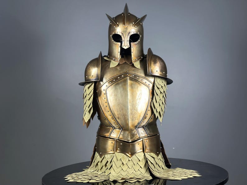 May include: A detailed bronze-colored suit of armor, including a helmet with spikes, shoulder guards, and chest plate. The armor has intricate detailing and a layered design on the shoulders and lower torso, suggesting a historical or fantasy theme.
