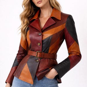 May include: A multi-colored leather jacket with a belted waist. The jacket features a patchwork design in shades of brown, black, and orange. It has a collared neckline and button closures. The model is wearing blue jeans.