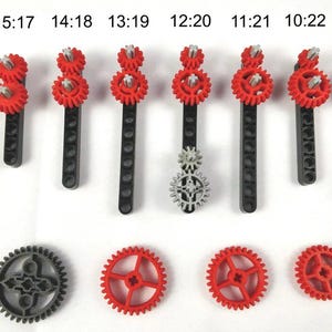 May include: An assortment of red and gray plastic gears and gear assemblies. The gears are of various sizes and are arranged in a pattern. The image also includes black plastic rods with red gears attached.