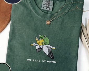 Geborduurd We Read At Dawn T-shirt, grappige kikker en gans leesgrage T-shirt, readershirt, boekenliefhebber cadeau, gezellige literaire top, uniseks grafisch T-shirt
