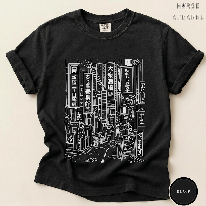 Puede incluir: Camiseta negra con un dibujo lineal blanco que representa una escena callejera japonesa, con letreros, edificios y figuras. El dise&ntilde;o incorpora texto japon&eacute;s. La camiseta tiene las mangas enrolladas y la marca "MORSE APPAREL" es visible.