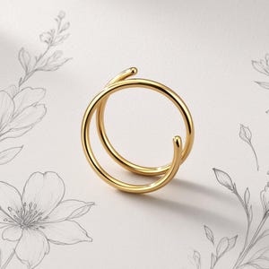 Könnte beinhalten: Ein polierter goldfarbener Ring mit einem Doppelring-Design und einem glatten, durchgehenden Metallband. Der Ring hat eine offene, überlappende Struktur, die zwei kreisförmige Schichten bildet, mit einer hellen, reflektierenden Oberfläche und abgerundeten Enden.