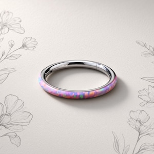 May include: A circular hinged hoop ring featuring a polished silver-tone metal finish on the inner band and a vibrant, multi-colored synthetic opal inlay on the outer surface, displaying iridescent pink, blue, and green flecks throughout.