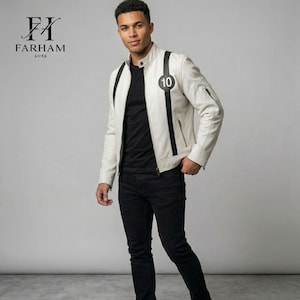 Peut inclure: Veste en cuir crème avec des détails noirs, un col montant et un écusson circulaire avec le chiffre 10. La veste a une fermeture éclair et des rayures noires. Le logo Farham Luxe est visible en haut à gauche.