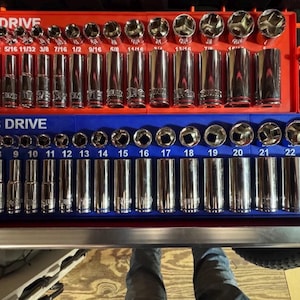 Könnte beinhalten: Ein Satz verchromter Steckschlüssel und Ratschen, angeordnet in einer rot-blauen Aufbewahrungsschale. Die Schale ist mit "3/8 DRIVE" beschriftet und enthält verschiedene Steckschlüsselgrößen, von 6 mm bis 24 mm.