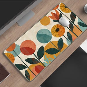 Puede incluir: Alfombrilla de ratón rectangular con un diseño floral en naranja, turquesa y amarillo. Las flores tienen un estilo retro, con grandes pétalos circulares y hojas de color verde oscuro. Un ratón de ordenador blanco está sobre la alfombrilla.