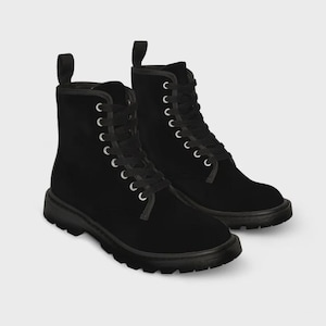 May include: A pair of black combat boots with a matte finish. The boots have a lace-up design with silver eyelets and a pull tab at the back. The soles are thick and black.