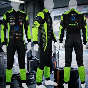 Puede incluir: Traje de carreras negro y verde neón con múltiples logotipos y texto. El traje presenta detalles en verde neón en las mangas, piernas y laterales, con un patrón de panal en los laterales. Se muestra en un maniquí.