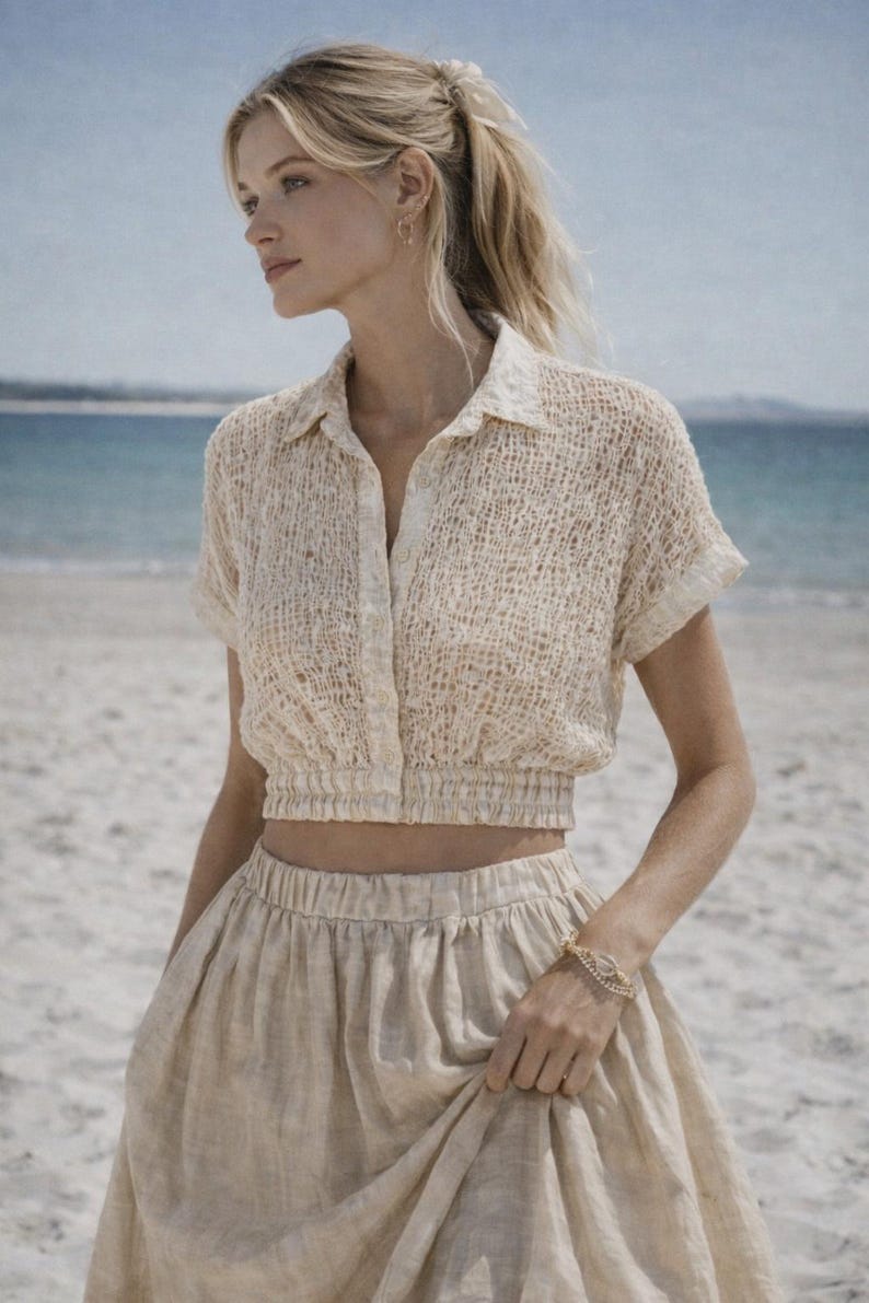 May include: A beige, short-sleeved crop top and matching skirt. The top has a collared neckline and button-down front. The skirt is a flowing, midi-length design. The outfit is made of a textured fabric, perfect for a beach day.