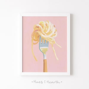 May include: A framed art print featuring a fork with a tangle of spaghetti. The fork is light blue with a wooden handle, and the pasta is a golden yellow against a pink background. The text "+ Hues & Hearth +" is at the bottom.